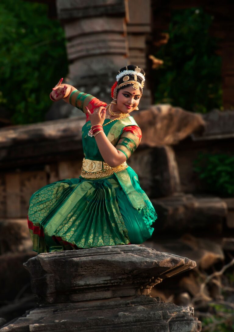 A classical Indian dancer performs in vibrant attire against a historic backdrop
